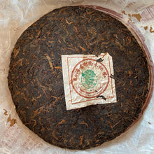 Load image into Gallery viewer, 2005 XingHai "Yin Kong Que - Gu Shu Qiao Mu" (Silvers Peacock - Menghai Old Arbor Tree) 501 Batch Cake 357g Puerh Ripe Tea Shou Cha