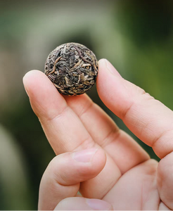 Hand holding a spherical tea cake with text describing its characteristics