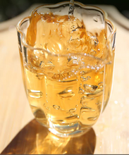 Load image into Gallery viewer, Glass of yellow liquid being poured with text on a black background