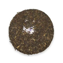 Load image into Gallery viewer, Compressed Chinese puerh tea cake with visible loose tea leaves on a white background