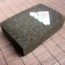 Load image into Gallery viewer, compressed dark puerh tea brick on bamboo mat