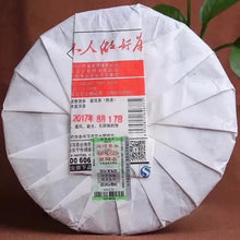 Charger l'image dans la galerie, Wrapped pu-erh tea cake with Chinese labels and barcode, photographed on a brown background.