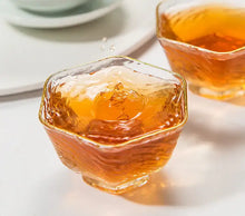 Load image into Gallery viewer, Close-up of Chinese tea in textured glass teacups with amber liquid, splash captured