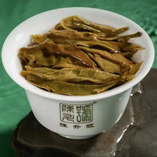 Load image into Gallery viewer, Brewed puerh tea leaves in a white gaiwan on a green background