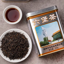 Load image into Gallery viewer, Loose leaf Chinese black tea in a white dish, brewed tea in a cup, and decorative tea tin