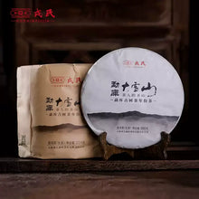 Load image into Gallery viewer, Chinese puerh tea cake and paper-wrapped tea, pressed tea disc on wooden stand, traditional packaging