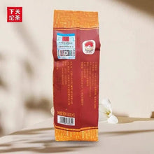 Load image into Gallery viewer, Chinese puerh tea bag with orange and red packaging, barcode, and Chinese text, upright on table
