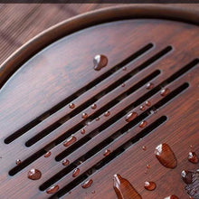 Load image into Gallery viewer, Wooden surface with water droplets on a wooden background Product Name: Round Tea Tray

Material: Bamboo + Laminate Board Base

Size:

Small : Diameter 25 * Height 5 cm

Medium: Diameter 29 * Height 5 cm

Large : Diameter 38 * Height 5 cm



This Round Tea Tray is an exquisite piece of craftsmanship, designed for the ritual of Gongfu tea, a traditional Chinese method of tea preparation that focuses on the aesthetic presentation and sharing. The tray is constructed from high-quality bamboo, a material revere