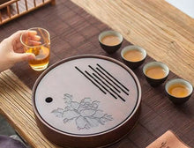 Load image into Gallery viewer, Tea set with a central round tea tray on a wooden table. Product Name: Round Tea Tray

Material: Bamboo + Laminate Board Base

Size:

Small : Diameter 25 * Height 5 cm

Medium: Diameter 29 * Height 5 cm

Large : Diameter 38 * Height 5 cm



This Round Tea Tray is an exquisite piece of craftsmanship, designed for the ritual of Gongfu tea, a traditional Chinese method of tea preparation that focuses on the aesthetic presentation and sharing. The tray is constructed from high-quality bamboo, a material revered