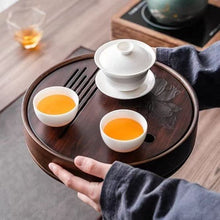 Load image into Gallery viewer, Tea set with three white cups and a white teapot on a wooden tray, held by a person. Product Name: Round Tea Tray

Material: Bamboo + Laminate Board Base

Size:

Small : Diameter 25 * Height 5 cm

Medium: Diameter 29 * Height 5 cm

Large : Diameter 38 * Height 5 cm



This Round Tea Tray is an exquisite piece of craftsmanship, designed for the ritual of Gongfu tea, a traditional Chinese method of tea preparation that focuses on the aesthetic presentation and sharing. The tray is constructed from high-qualit