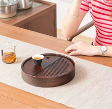 Load image into Gallery viewer, Person enjoying a cup of tea with a wooden tea tray on a table.