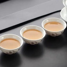 Load image into Gallery viewer, Three porcelain teacups with Chinese tea on a dark table, traditional tea ceremony style.