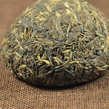 Carica l'immagine nel visualizzatore di Gallery, Close-up of compressed puerh tea ball on brown cloth, showing dried tea leaves.