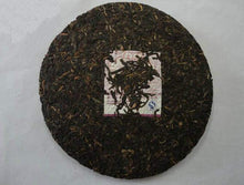 Load image into Gallery viewer, Compressed Chinese puerh tea cake with visible tea leaves and central label on white background