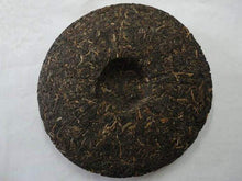 Load image into Gallery viewer, Compressed pu-erh tea cake with dark, textured surface on white background