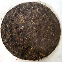 Carica l'immagine nel visualizzatore di Gallery, compressed puerh tea cake on white paper, whole leaf texture visible