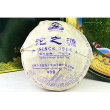 Load image into Gallery viewer, Wrapped Chinese puerh tea cake with blue Chinese and English text, displayed on a table