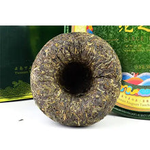 Load image into Gallery viewer, Compressed Yunnan puerh tea cake, round tuocha shape, with green packaging in background