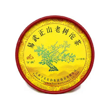 Load image into Gallery viewer, Yunnan Chinese tea cake with yellow label, green tea tree illustration, and red rim