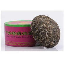 Charger l'image dans la galerie, Chinese Pu-erh tea tuocha cake with green and pink packaging, pressed tea leaves visible