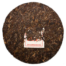 Load image into Gallery viewer, Whole compressed puerh tea cake with embedded paper label, dry tea leaves visible