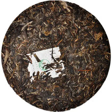 Load image into Gallery viewer, Sheng puerh tea cake with visible tea leaves and embedded paper label