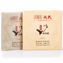 Carica l'immagine nel visualizzatore di Gallery, Two packages of Chinese pu-erh tea cakes with bird and leaf logo, Chinese text on wrapping.
