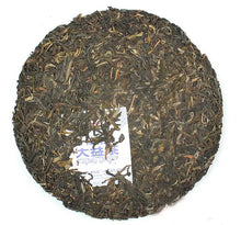 Load image into Gallery viewer, Whole round puerh tea cake with visible tea leaves and inserted paper label