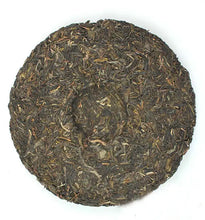 Load image into Gallery viewer, Compressed puerh tea cake with dark loose tea leaves on white background