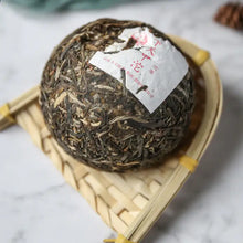 Load image into Gallery viewer, Chinese puerh tea ball with leaf texture and label on bamboo tray