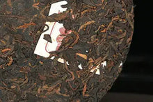 Load image into Gallery viewer, Compressed Chinese puerh tea cake with dark tea leaves and embedded paper ticket