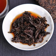 Load image into Gallery viewer, Brewed ripe puerh tea leaves on white dish, showcasing dark color and rich tea liquor