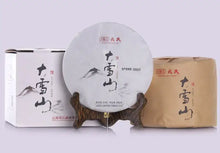 Load image into Gallery viewer, Chinese Pu-erh tea cake with mountain illustration, displayed with paper and box packaging