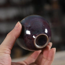 Load image into Gallery viewer, Hand holding a small glazed ceramic Chinese teacup with a deep purple finish