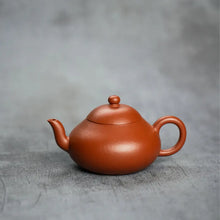 Load image into Gallery viewer, Yixing clay teapot with rounded shape on gray background, ideal for Chinese tea brewing.